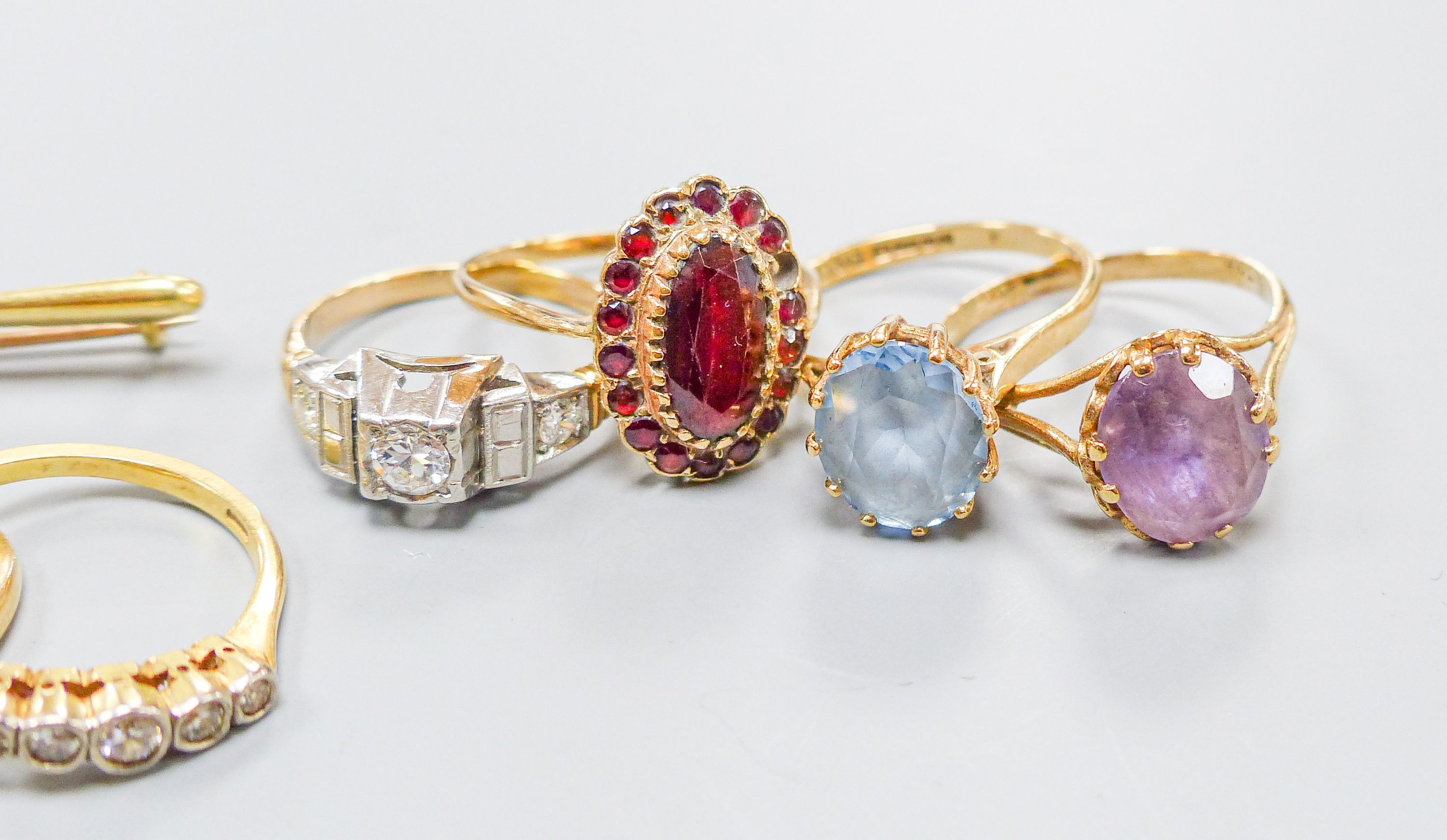 Three 18ct gold and gem set rings including two five stone half hoop(one stone missing) and a sapphire and diamond three stone, gross weight 7.3 grams, four 9ct and gem set rings and a 9ct pendant, gross 11.8 grams, a 15